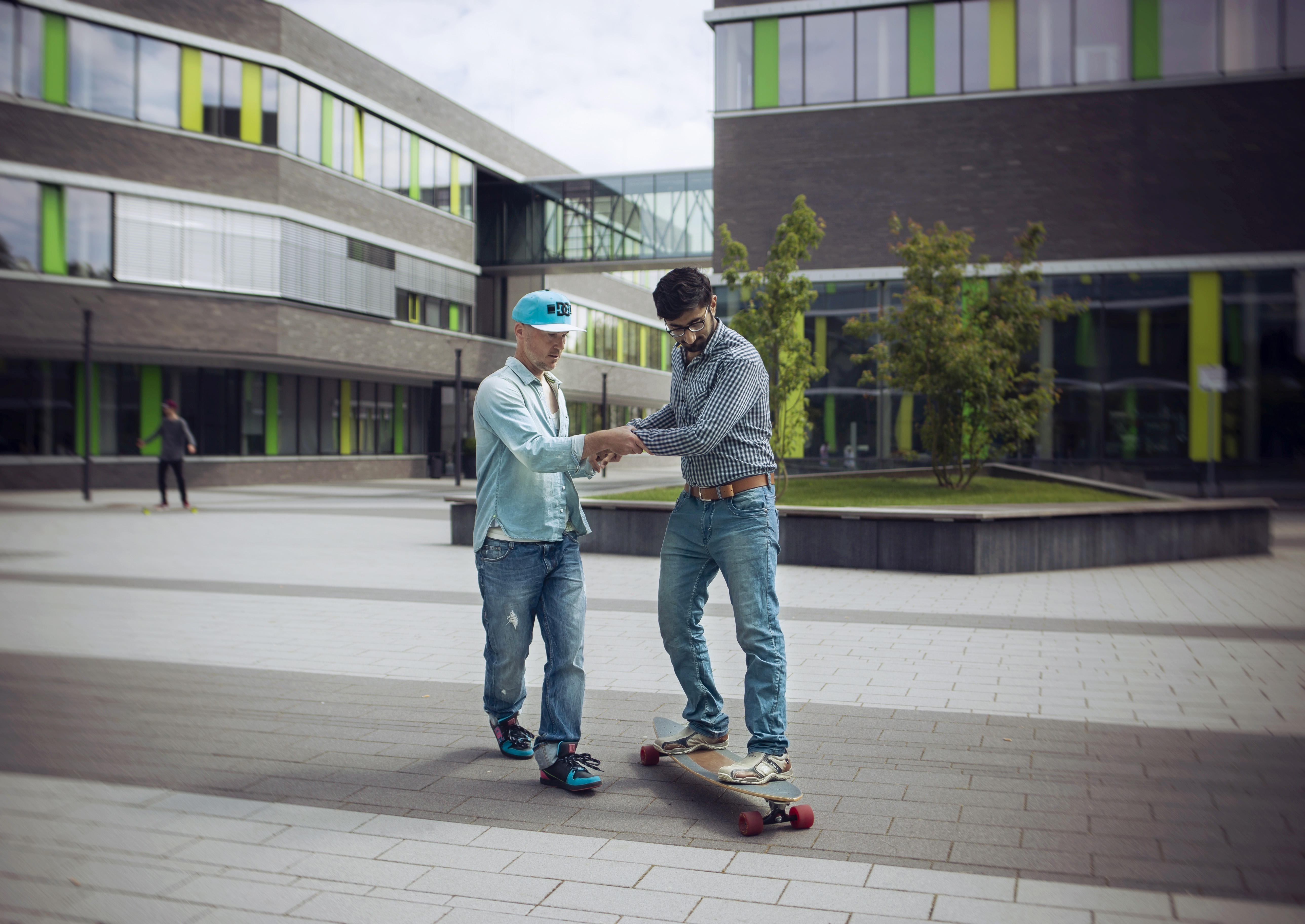 Person helps another person to ride a skateboard