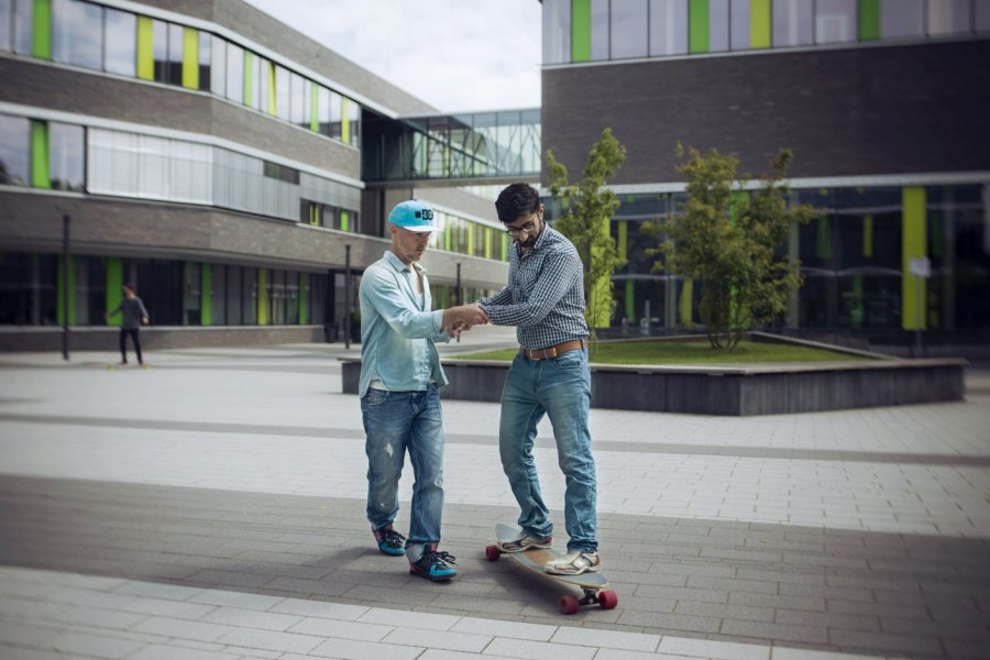 Person helps another person to ride a skateboard